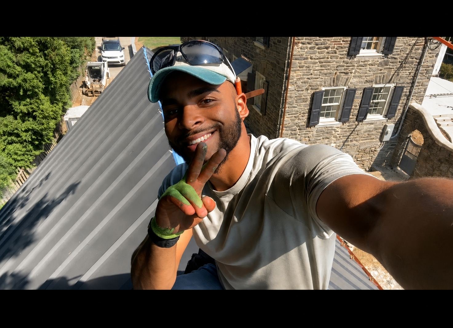 Miguel Cespedes on a metal roof installation job site — stone colonial background