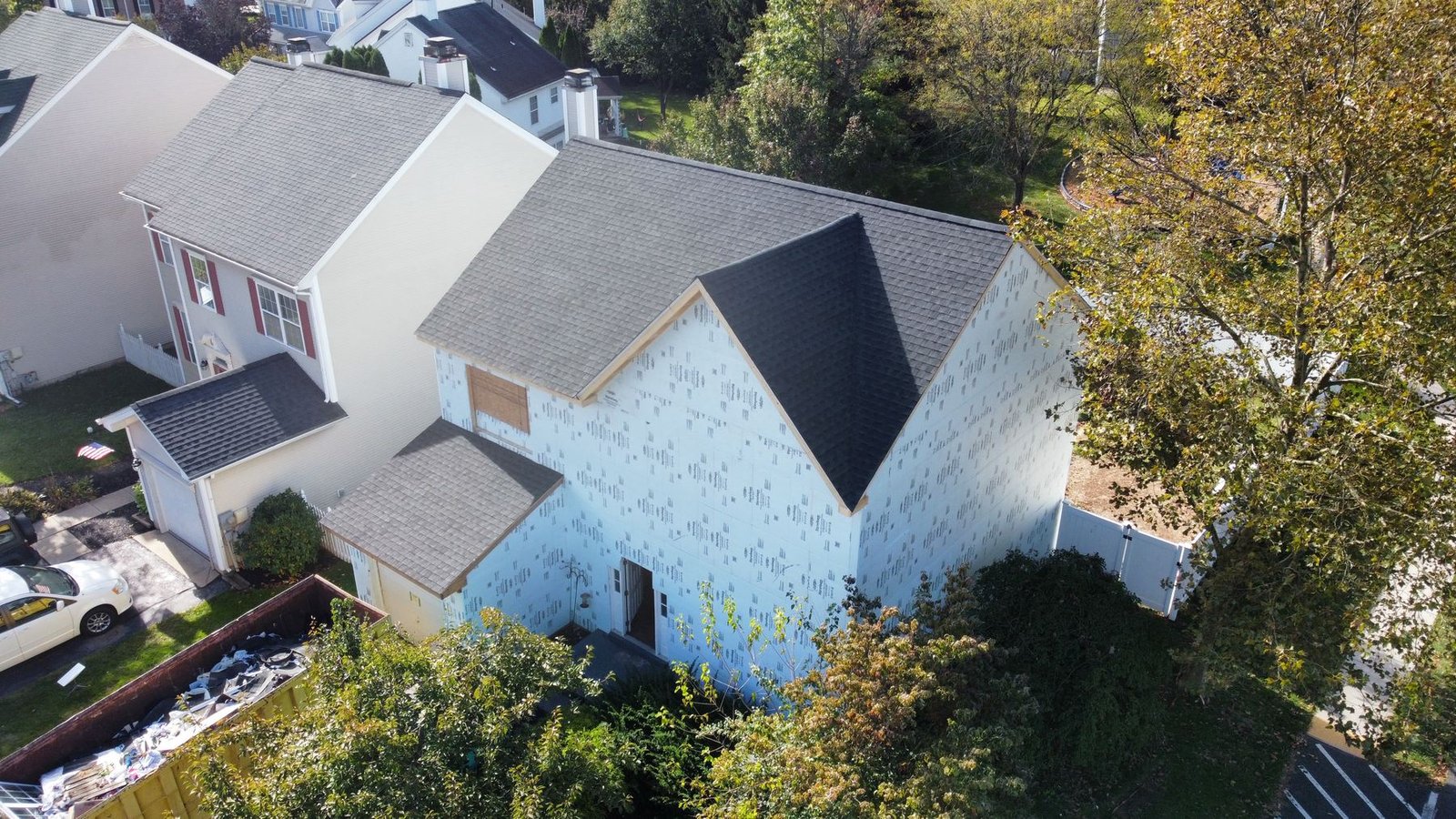 In-progress — rear view showing house wrap and new roof during exterior renovation, PA