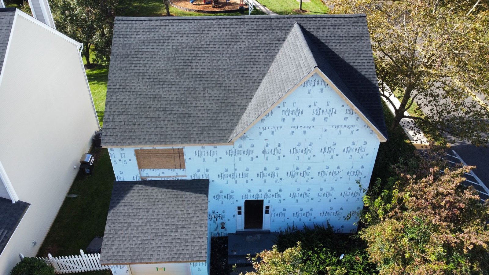 In-progress — top-down aerial showing new charcoal shingles and house wrap installed, PA