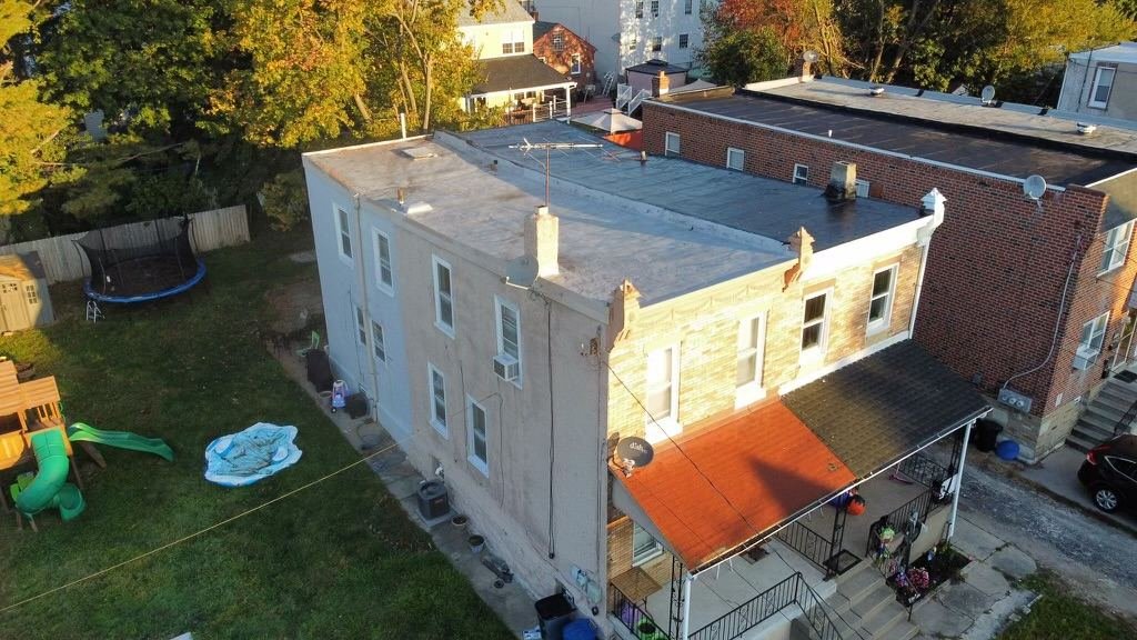Before — rear aerial of urban row home with failing flat roof system, PA
