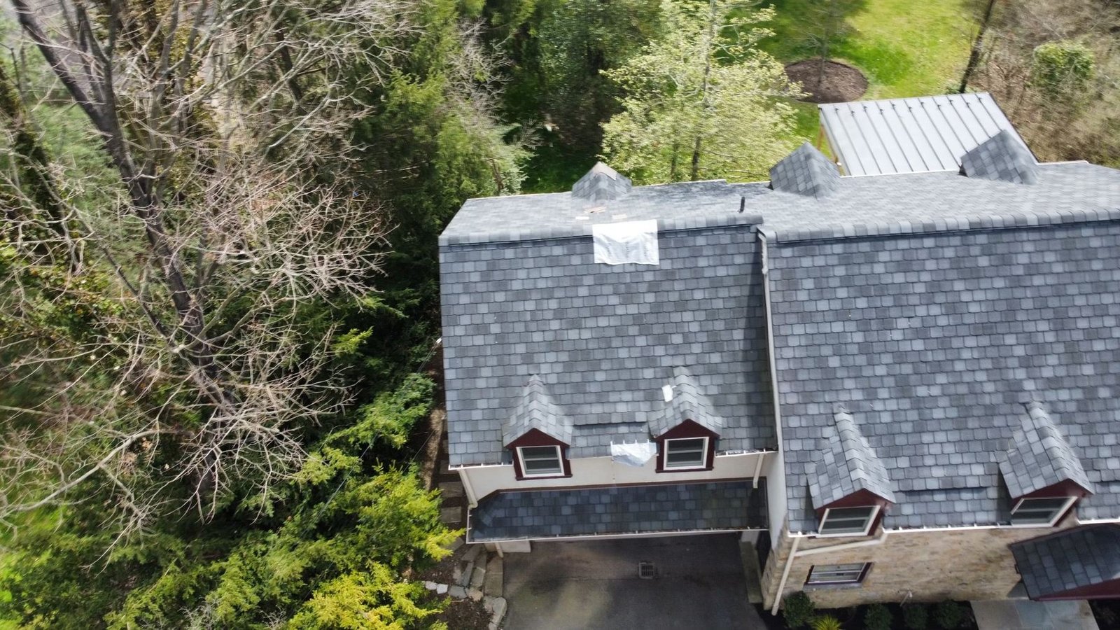Before — top-down aerial of dormer section with damaged shingles and emergency tarp, PA