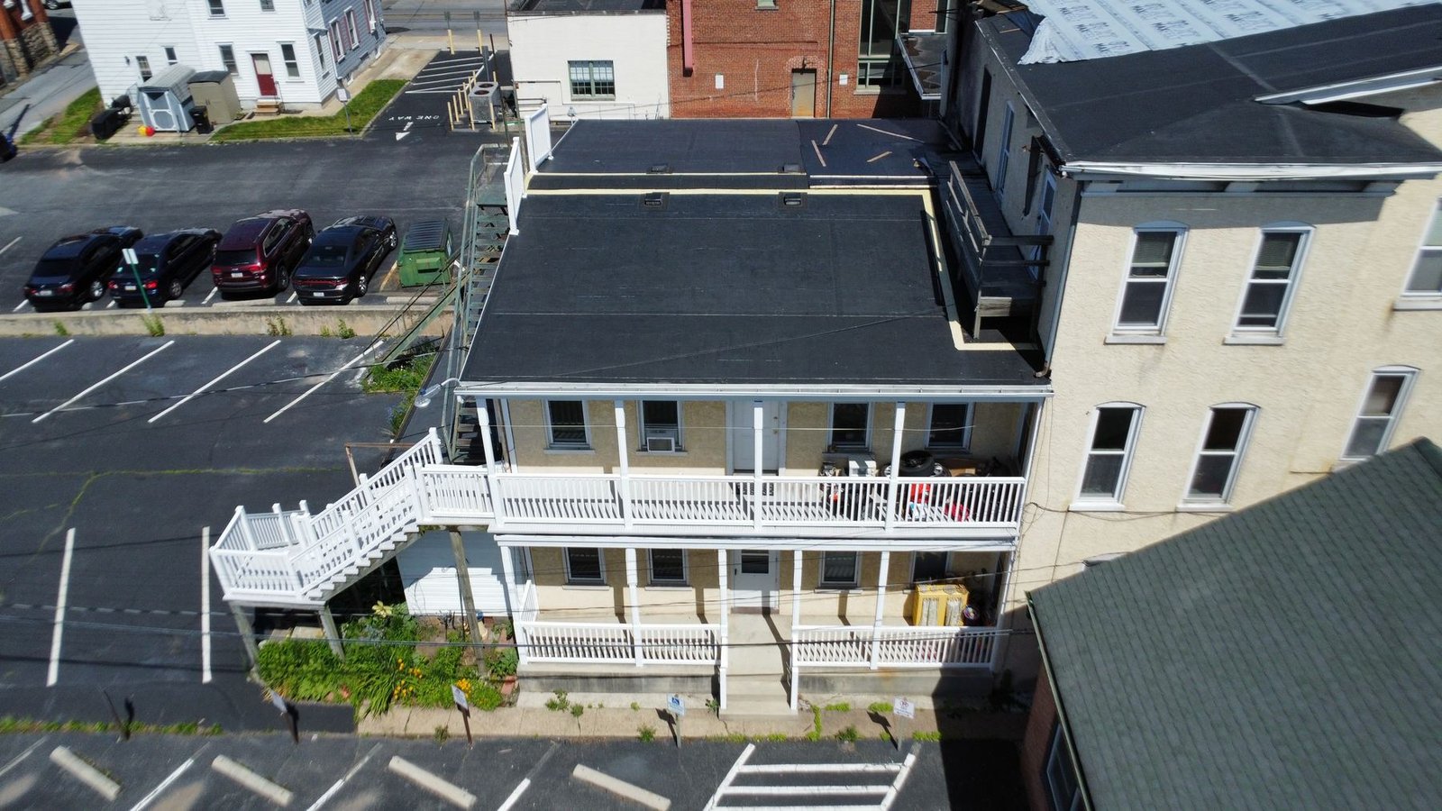 Before — front aerial of commercial building showing failing flat roof and white porch railings, PA