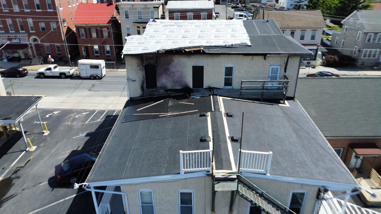 Before — aerial top-down showing failed commercial flat roof and adjacent fire-damaged structure, PA
