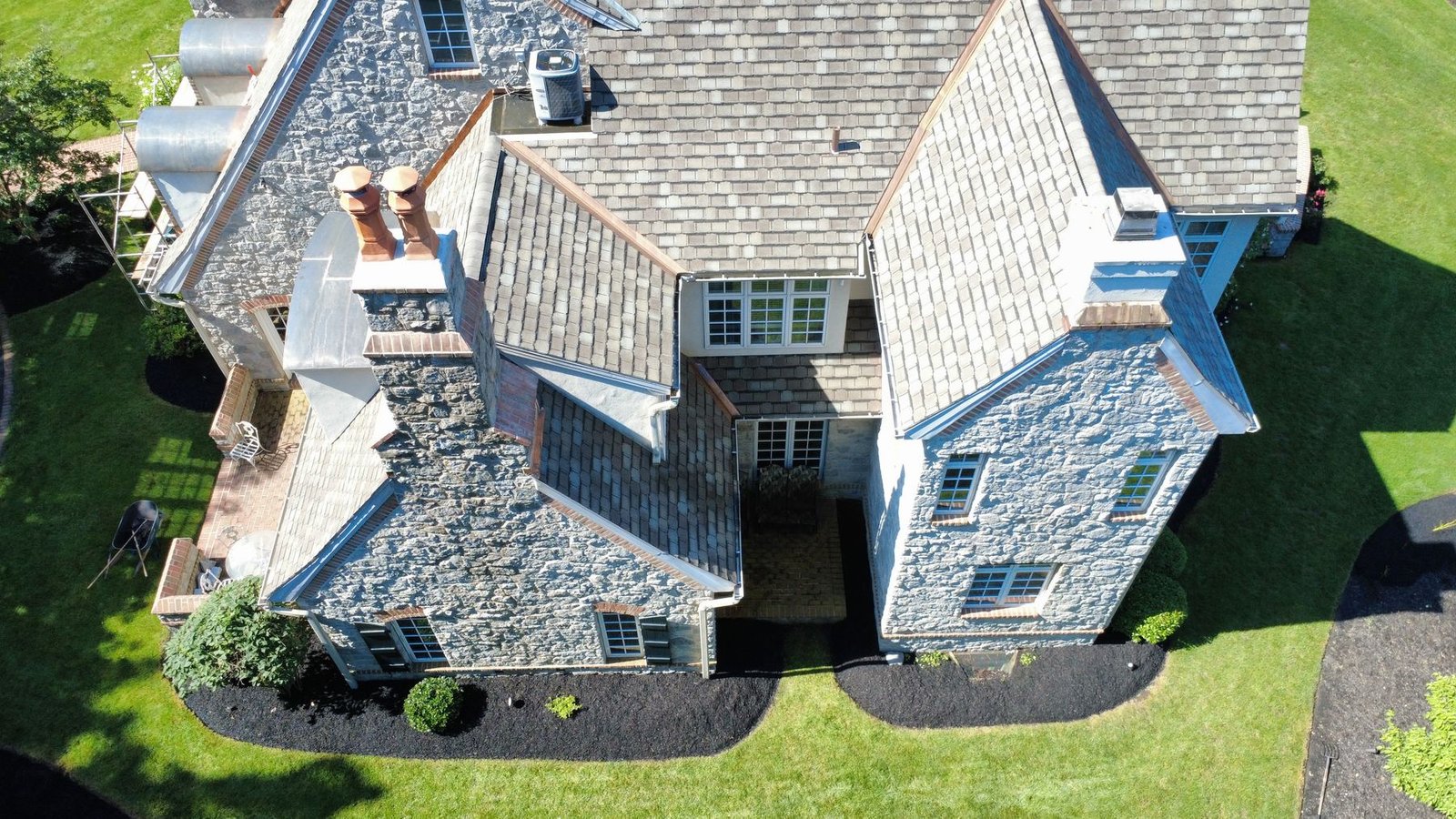 Close-up aerial of stone mansion roofing with copper accent details — Shelby Roofing Services PA