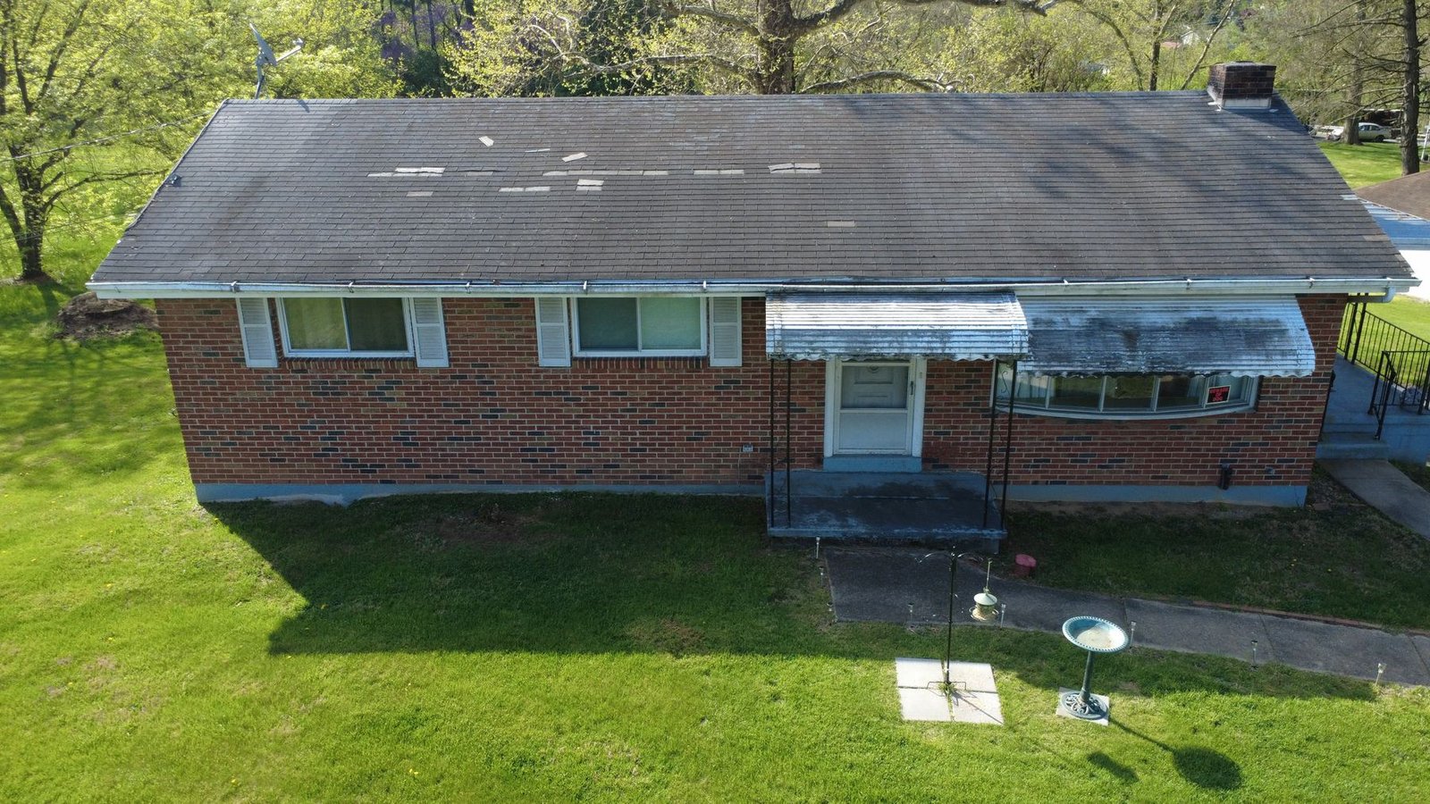Before — front aerial of brick ranch with severely weathered black shingles, PA