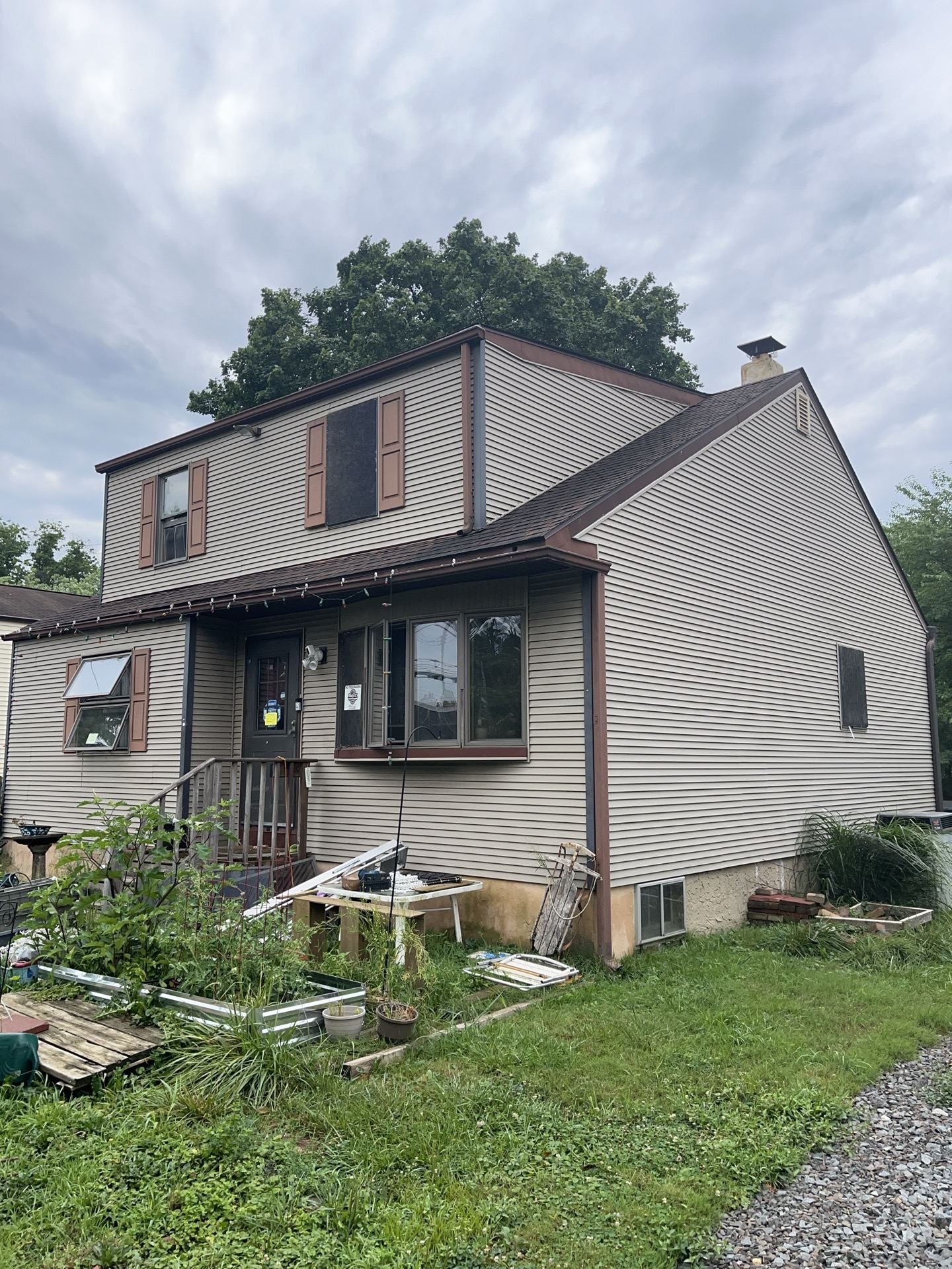 Before — front of gambrel cape with old beige siding and worn brown shingles, NJ