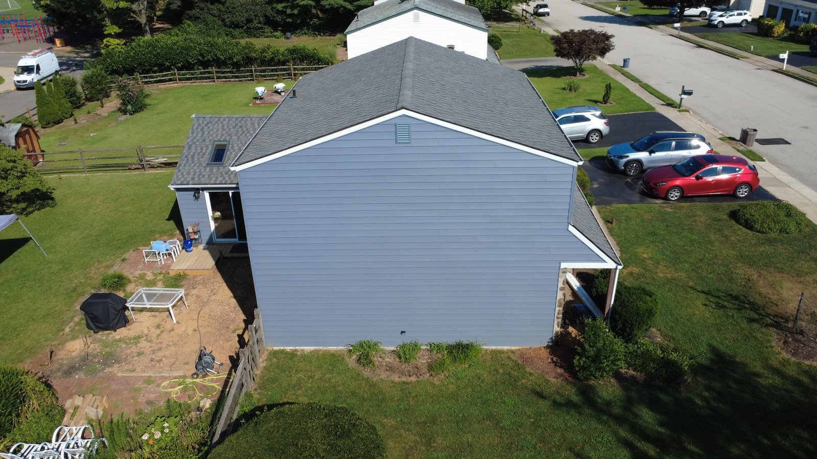After — top-down aerial of completed stone colonial with new shingles — Shelby Roofing Services PA