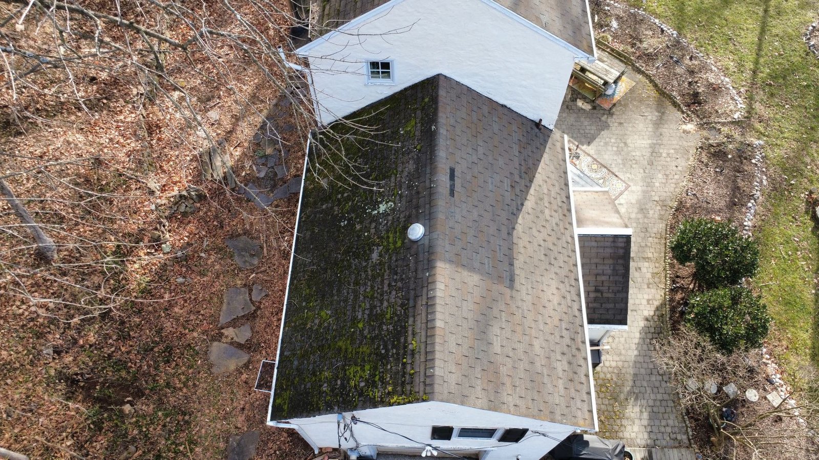 Before — top-down aerial of white cottage with severely moss-covered dark shingles, PA