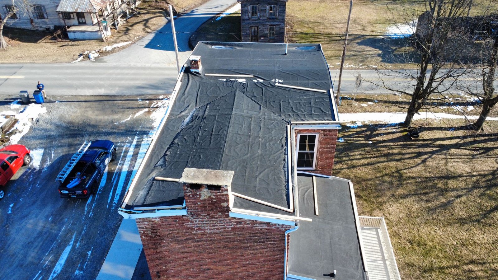 Before — aerial of historic brick building with deteriorated flat roof, PA
