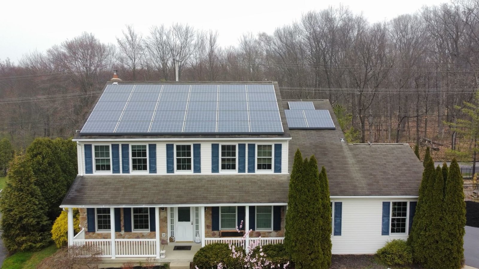 Before — front aerial view of colonial home with worn shingles and solar panels, PA