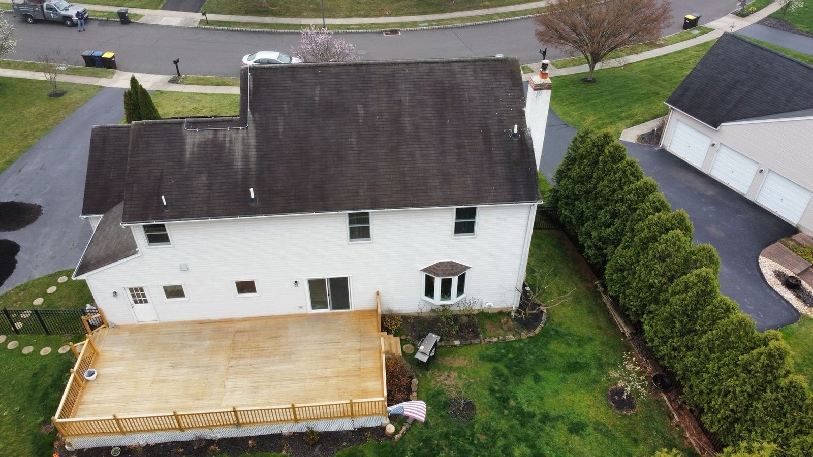 Before — rear aerial view of worn dark shingle roof and deck, PA