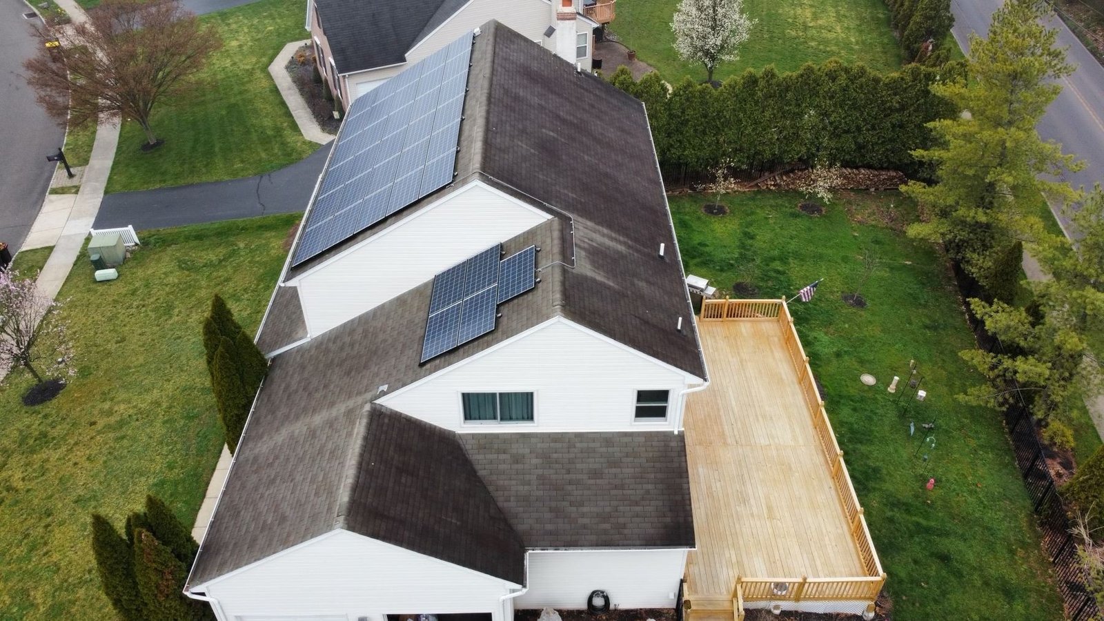 Before — side aerial view showing worn shingles and solar panels with deck, PA