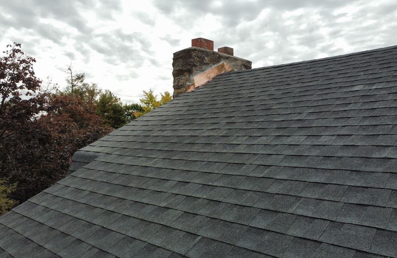 After — stone chimney with new copper flashing and charcoal shingles — Shelby Roofing Services PA