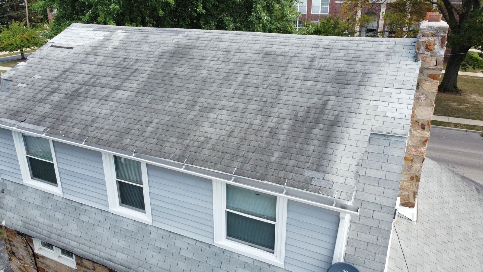Before — angled aerial showing stone chimney and algae-covered roof, PA