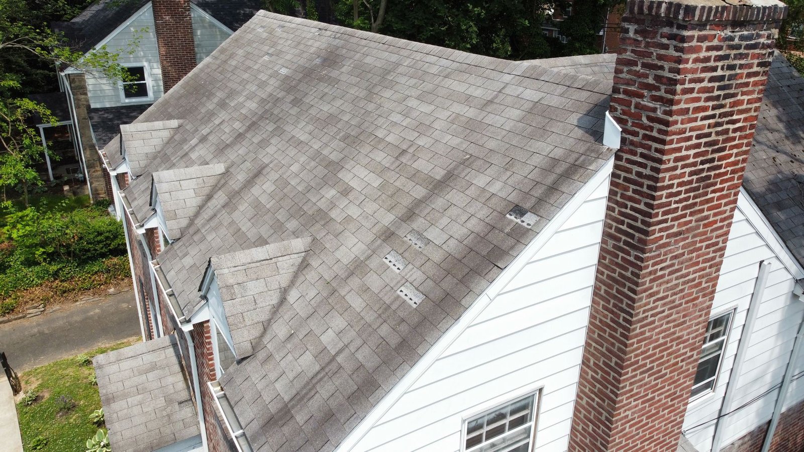 Before — angled aerial showing brick chimney and worn dormer roofing, PA