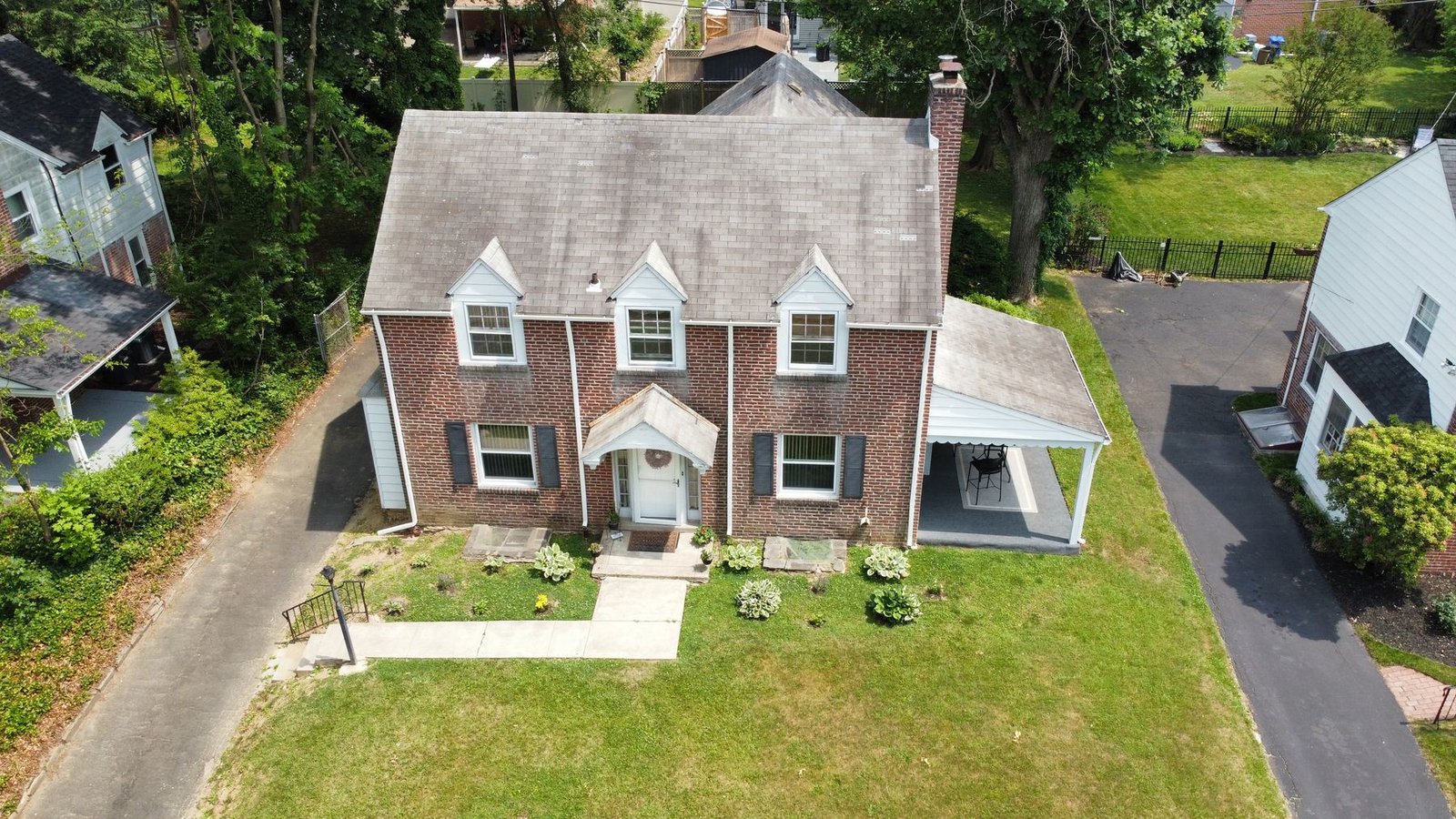 Before — front facade aerial of brick colonial with 3 dormers and old worn shingles, PA