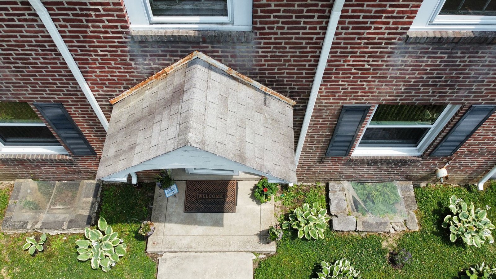 Before — close-up top-down of front entry porch roof with cracked worn shingles, PA