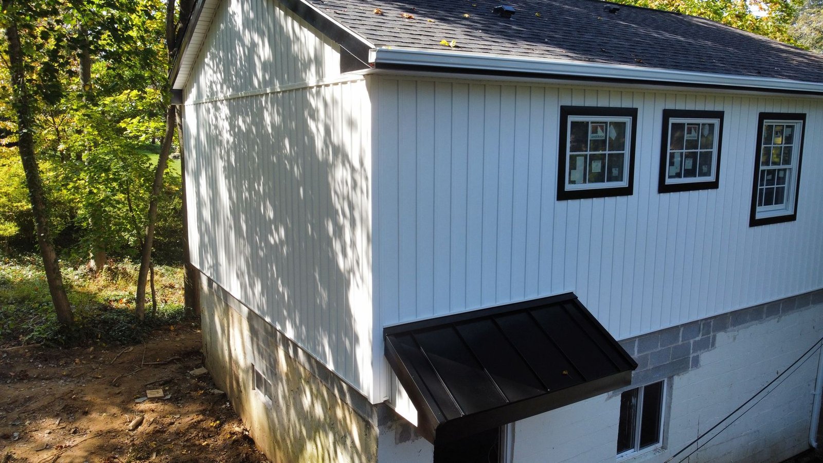 After — front-right angle showing new charcoal shingles, white siding, and standing seam awning — Shelby Roofing Services PA