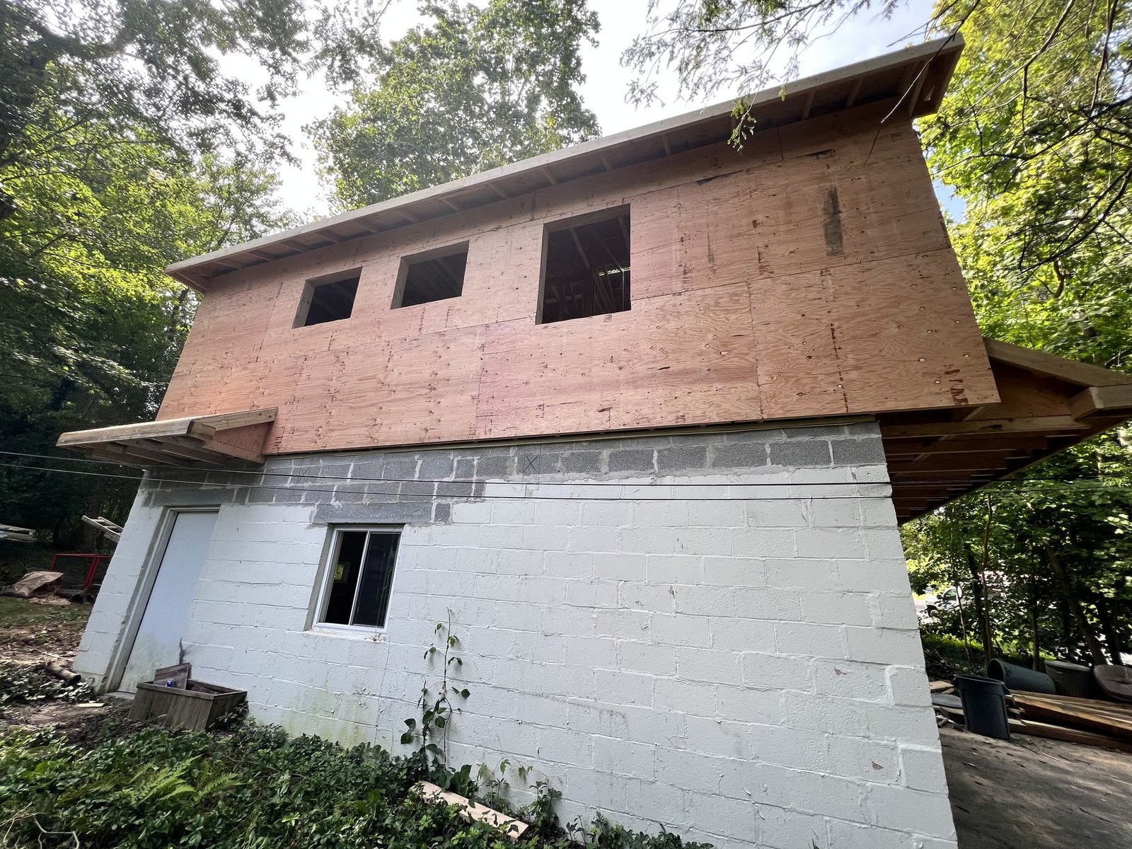 Before — front of structure showing bare OSB sheathing and rough window openings during new construction, PA